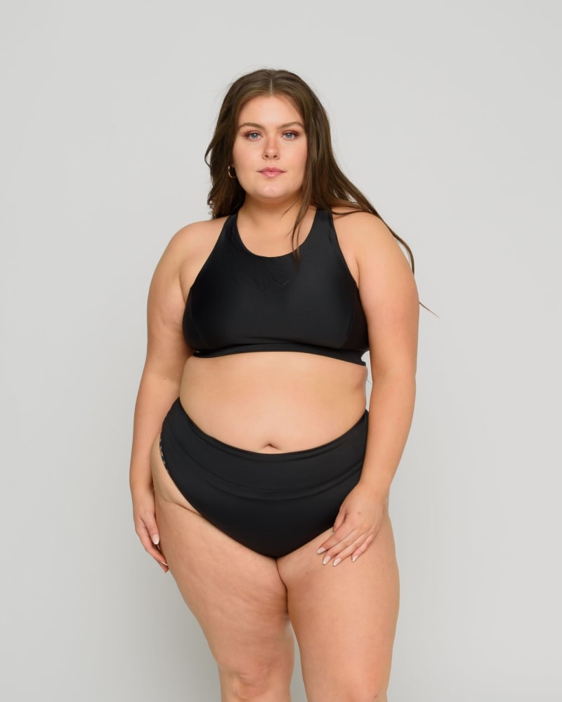 Front of a model wearing a size 10/12 Capri High Tide Cheeky Bottoms in Black by Wild Isles. | dia_product_style_image_id:295912